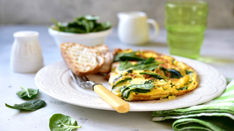 Omelet stuffed with spinach served with a side of bread