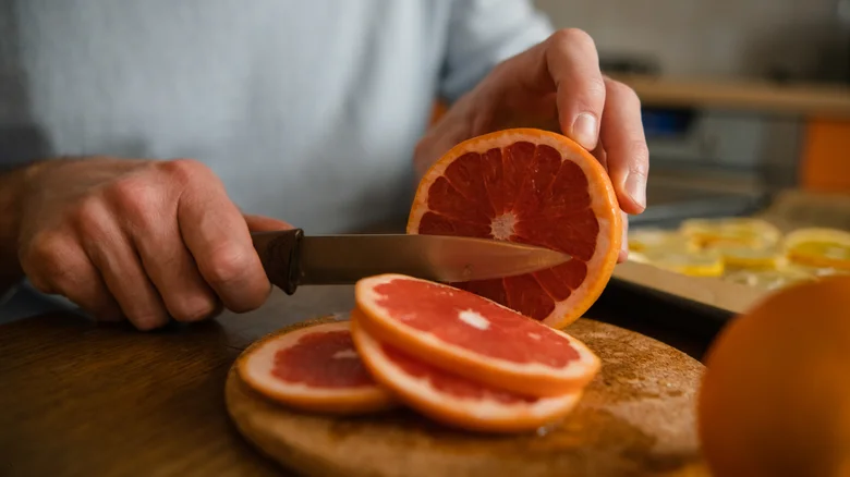 man cutting grapefruit into slices