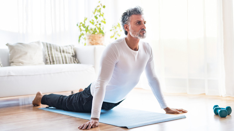 Man doing yoga at home on gym mat