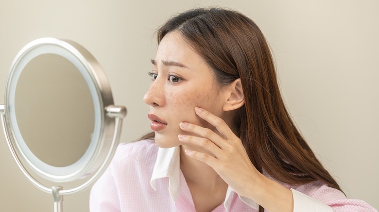 Woman examining her face closely