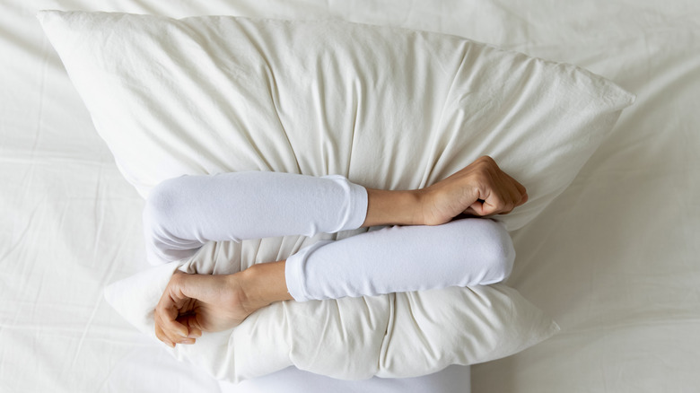 woman squeezing pillow with both arms