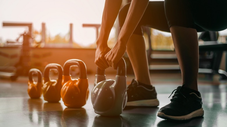 An athlete squatting to lift a kettle bell weight.