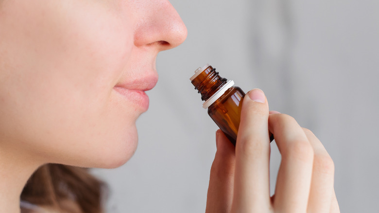 woman sniffing essential oil aromatherapy
