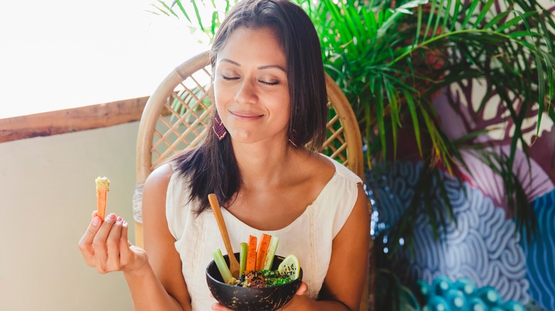Woman enjoying vegetables with hummus