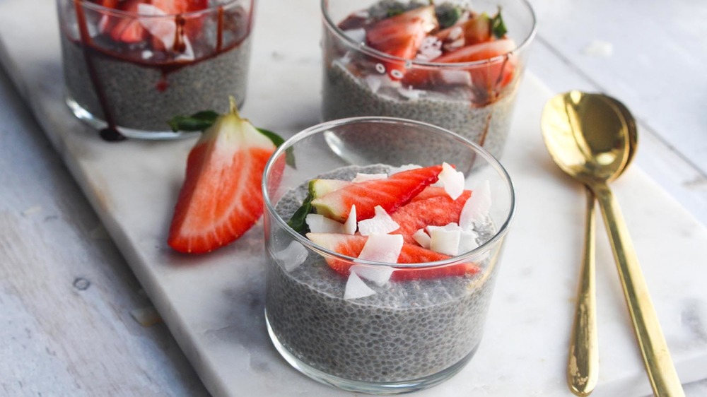 Chia seed pudding in a glass with sliced strawberries and shaved coconut on a table