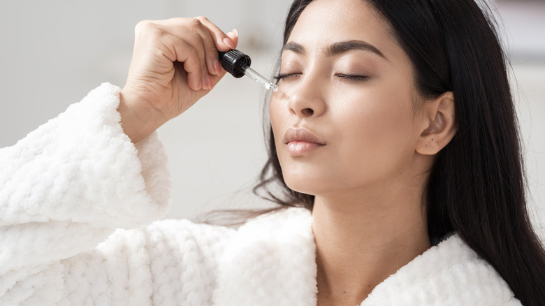 A woman puts a skin care product on her face