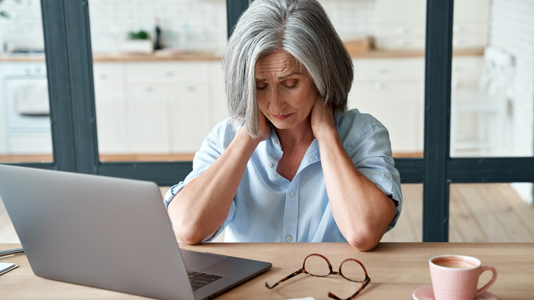 A woman has neck pain at her desk