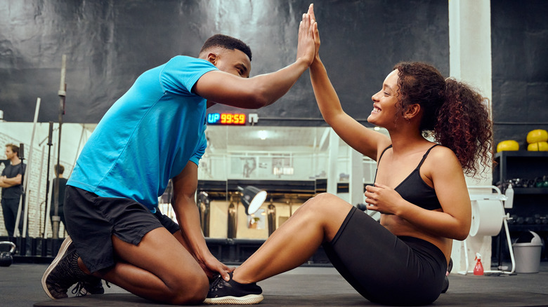 Trainer high-fiving client at gym
