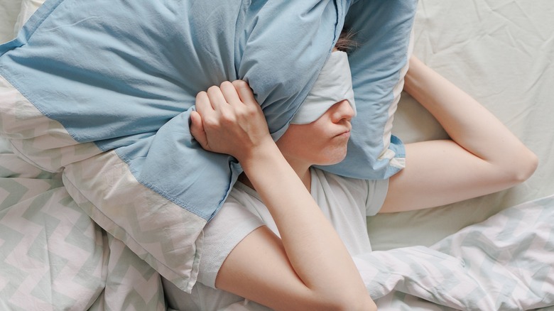 A sleeper holding a pillow over their head