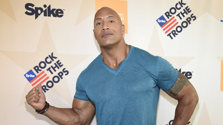 Dwayne "The Rock" Johnson standing in front of cameras at a military support event