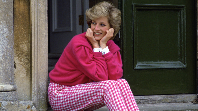 Princess Diana in a pink outfit, looking off to th eleft in front of doors.
