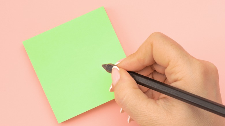 person writing on post-it note
