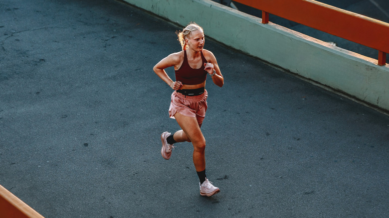 A woman running on a dark paved bath by herself.