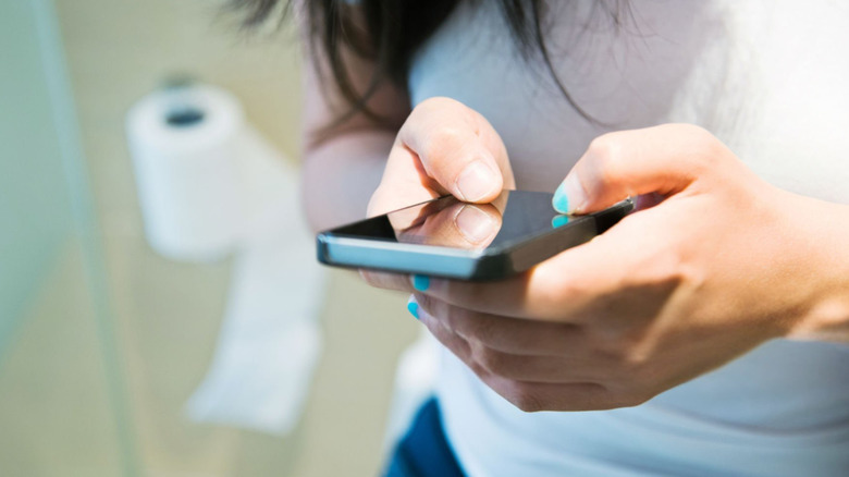 women using her cell phone in the restroom