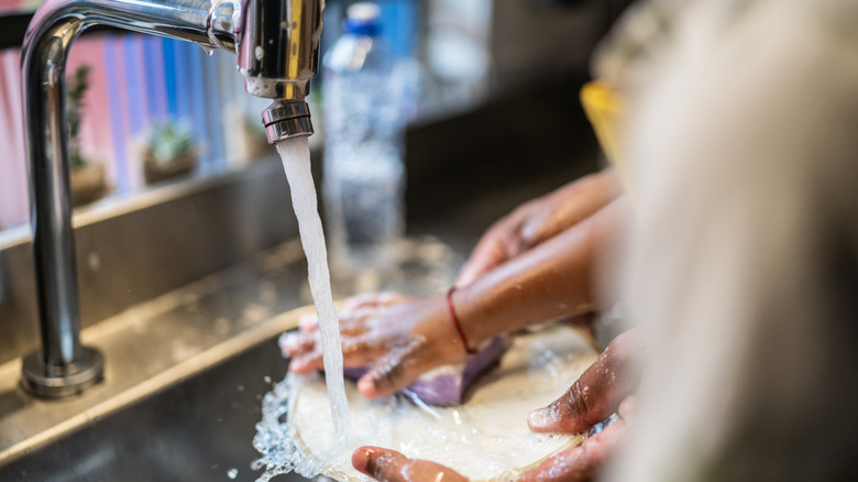 man and child washing dishes in kitchen sink at home