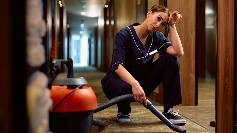 A woman looking annoyed while doing a vaccuum cleaner