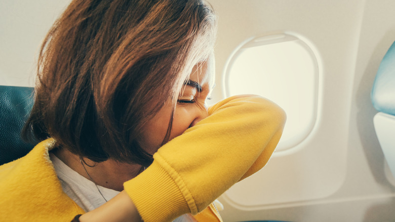 woman trying to avoid unpleasant smell on airplane