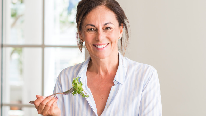 woman holding fork with leafy greens