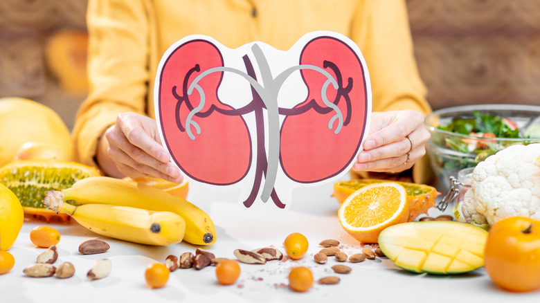 Person holding an image of a human's kidneys above a table covered with food