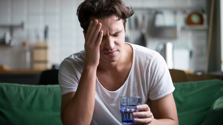 Man with a migraine holding his head in pain 