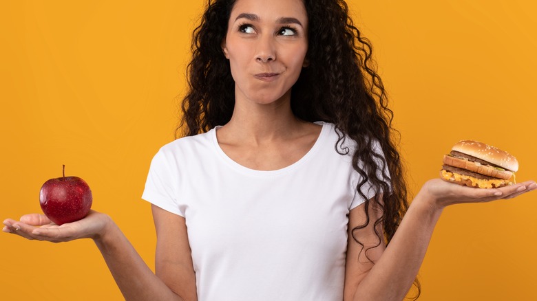 woman holding an apple and burger