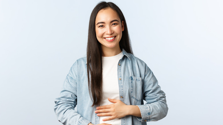 woman smiling while holding stomach