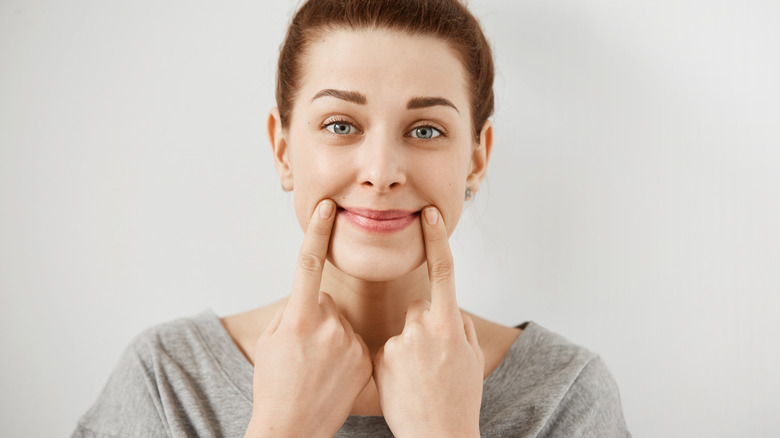 woman holding up corners of mouth in smile