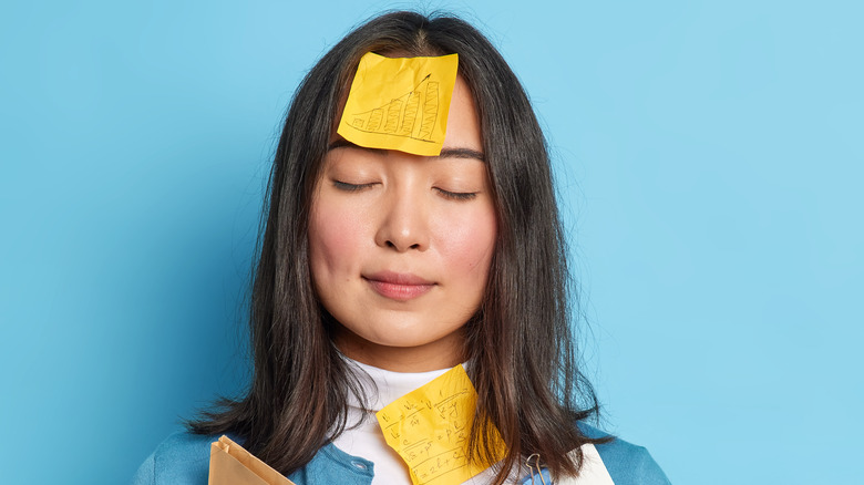 asian woman with books and notes all over her pretending to meditating