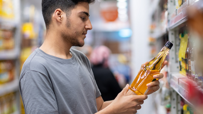 A person looking at a bottle of apple cider vinegar in the store