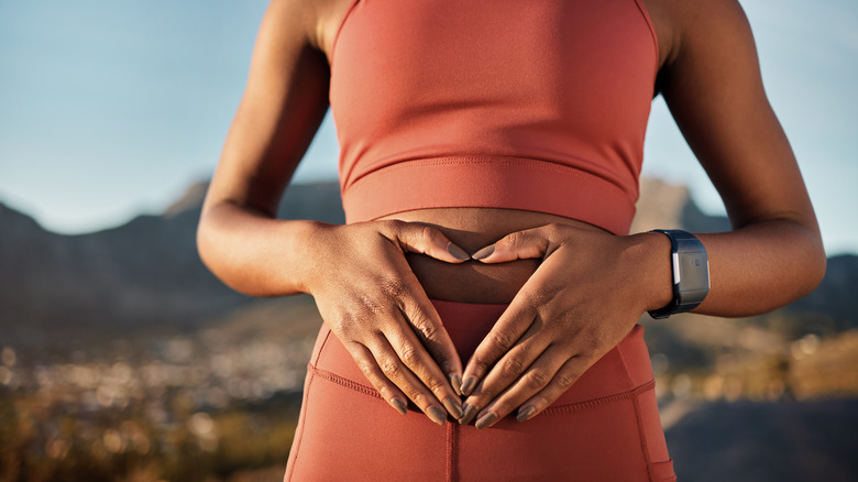 Athletic woman making a heart shape in front of her stomach hinting at a healthy gut