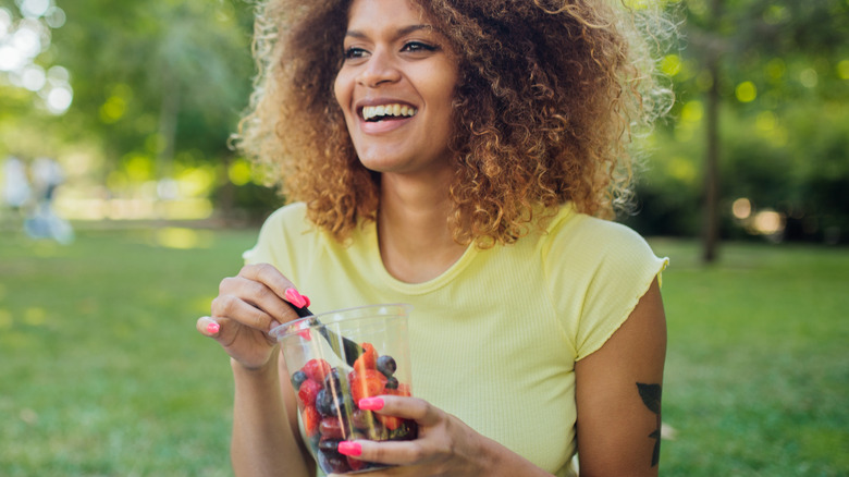 Smiling woman snacking on berries outside