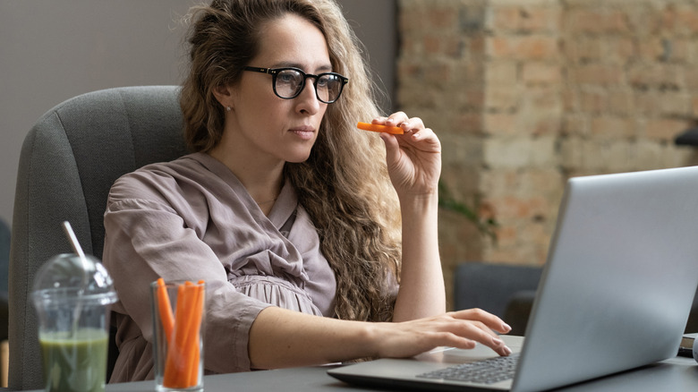 Woman eating a carrot while working