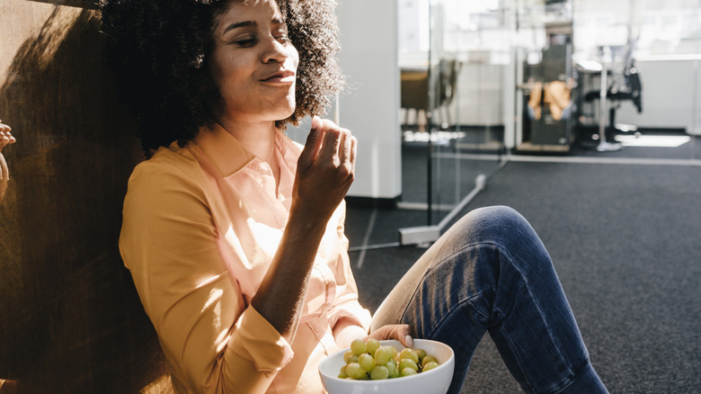 Woman leaning back and eating grapes