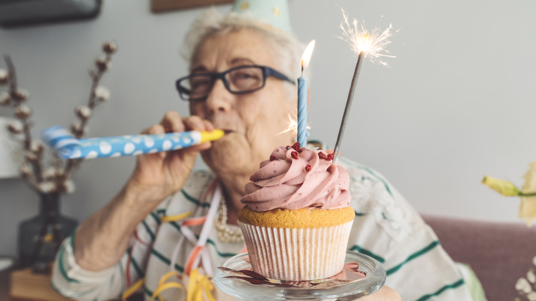 older woman celebrating a special occasion at home with a cupcake