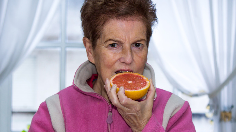 A senior woman eating a grapefruit