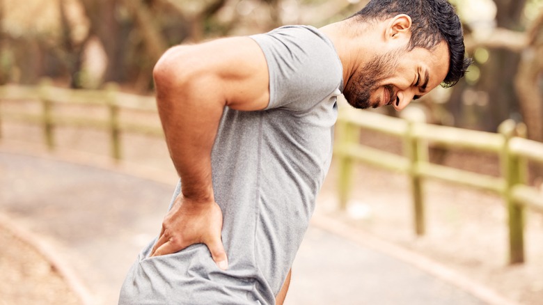 A younger man holding his back in discomfort