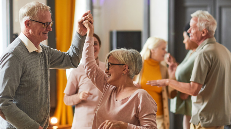 Seniors smiling and dancing while enjoying activities at a retirement home