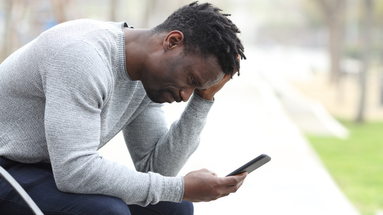 Upset man looking at phone