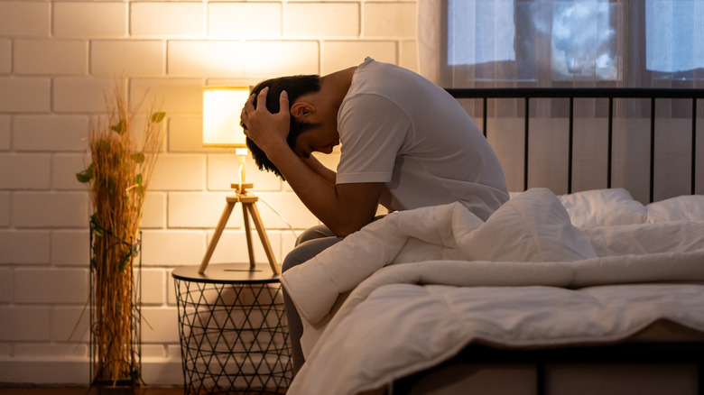 man sitting in bed struggling to sleep