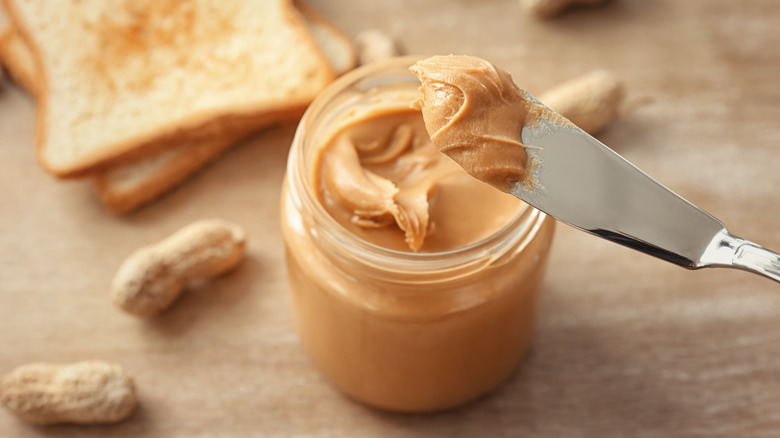 Someone scooping peanut butter with a knife