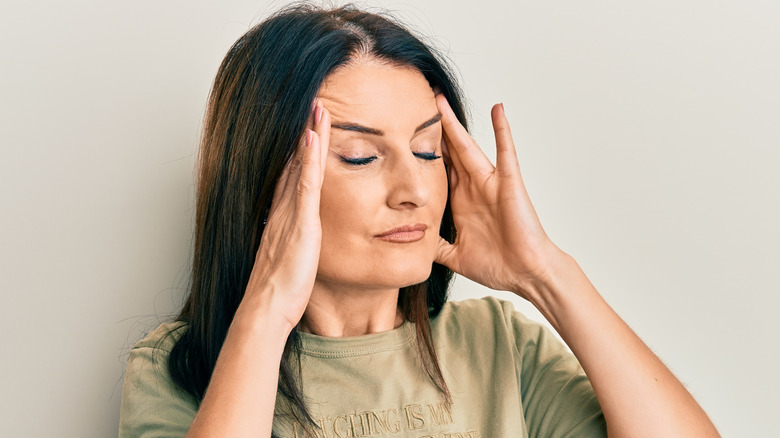Woman with closed eyes rubbing her temples