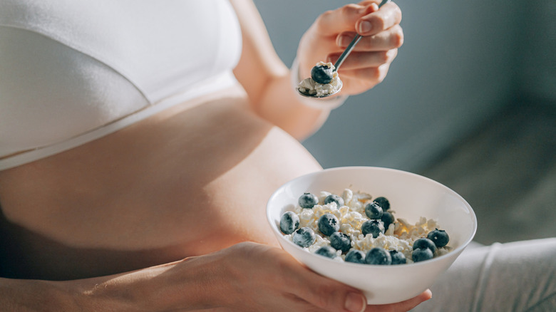 pregnant woman holding bowl of blueberries and ricotta