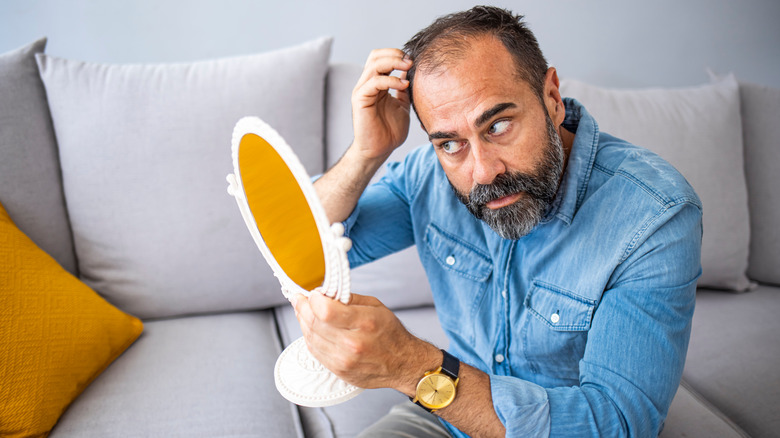 man inspects his hair in mirror