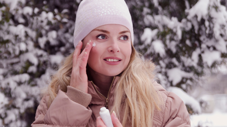 woman applying moisturizer outside