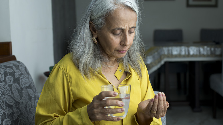 woman looking at the pills in her hand