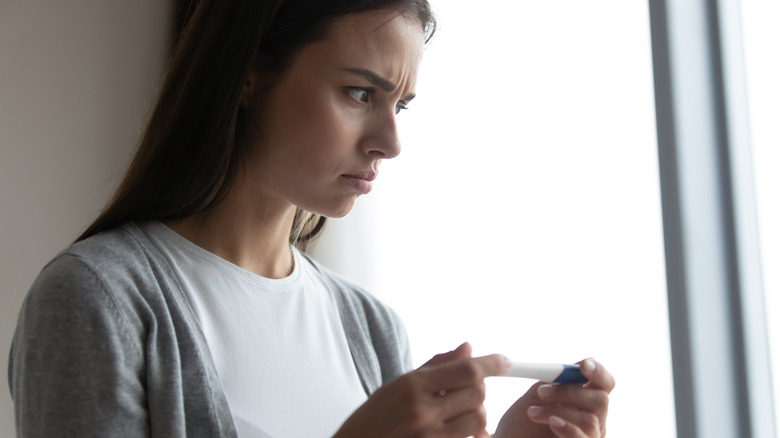 confused woman looking at pregnancy test