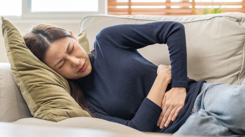 woman laying on the couch holding her stomach