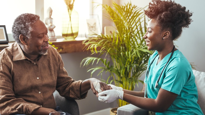 Older man holding hands with a healthcare worker