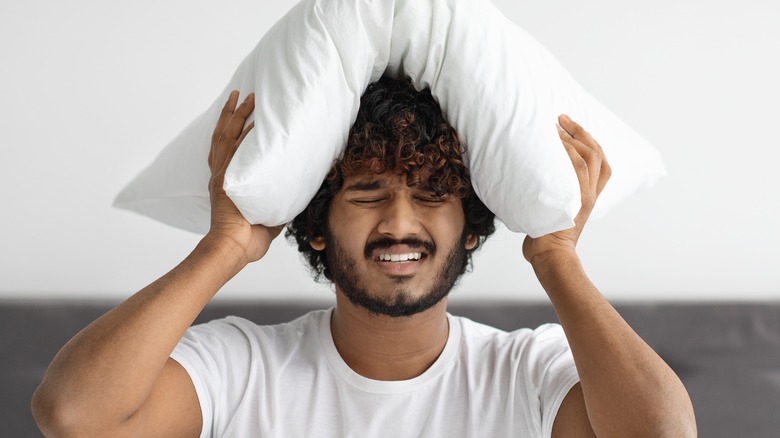 Man covering head with pillow
