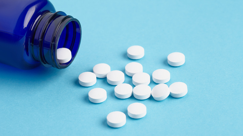 White tablets arranged spilling from an open bottle on its side